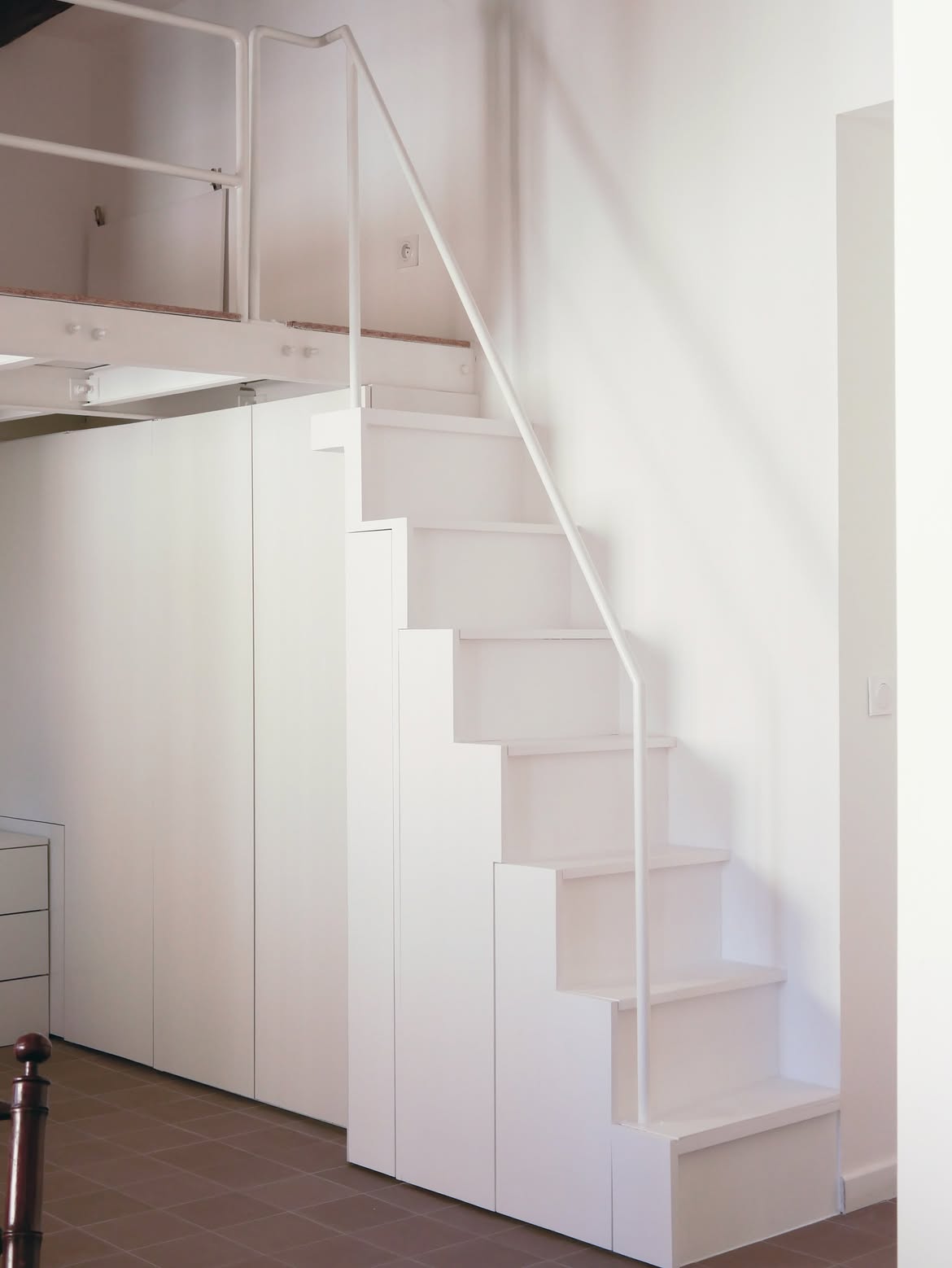 Escalier sur-mesure avec rangement, menant vers une petite mezzanine